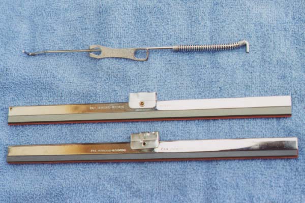 The photo doesn't show the detail intended. The clear lettering is not visible on the wiper arm clip, but the dull chrome finish is somewhat visible. The original wiper blade (top) has a slightly narrower frame than the only available reproduction (below). The positioning of the patent information is also located differently.