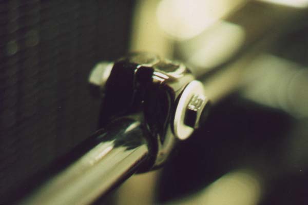 This close-up of one front license plate clip shows the original mounting hardware. The bolt is black enameled with the typical thick head. Like most bolts used on the Model A, they were classified as SAE "unfinished" bolts. This simply means there was NO machining on any part of the bolt head. The nut was raven finished, the flat washer was cadmium plated, and the lock washer was unfinished.