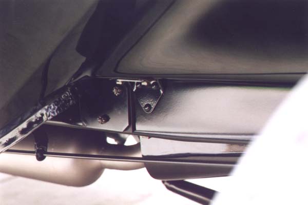 This view under the right front fender shows the contrast between the fender and frame. The frame was sprayed with an asphalt based "chassis black" which had little gloss and little resistance to solvents. The engine compartment pans were dipped like the fenders, but only one time or coat. The muffler was unfinished or plain steel. The rear motor mount to frame bolts were raven finish.