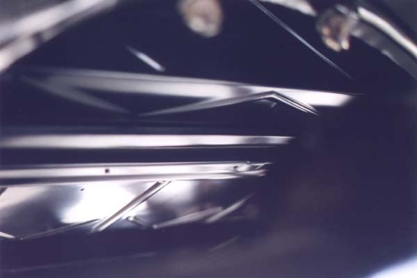 This view is of the bottom side of the body from the rear of the car. It shows the deep stampings of the front lip of the original rumble seat riser and the original "X" pan just forward of the riser.